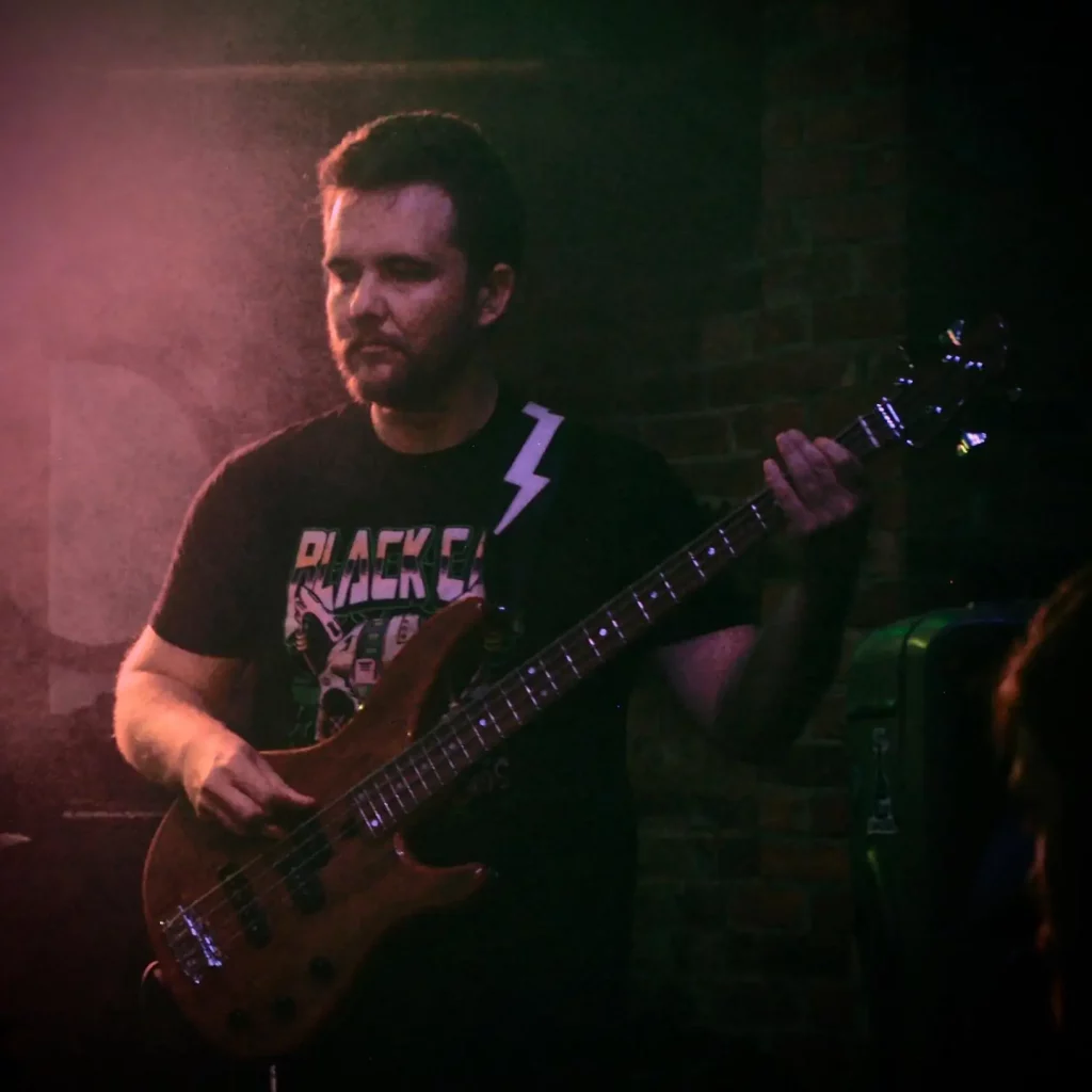 Josh Irlam, founder of Good Earth Marketing, playing bass guitar on stage.